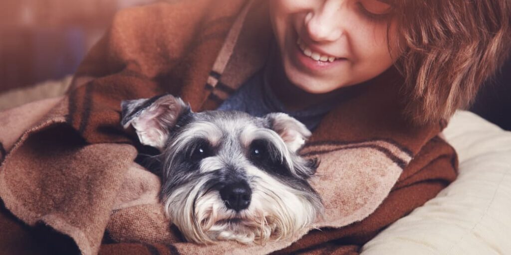 Une femme et un chien sont enroulés dans une couverture